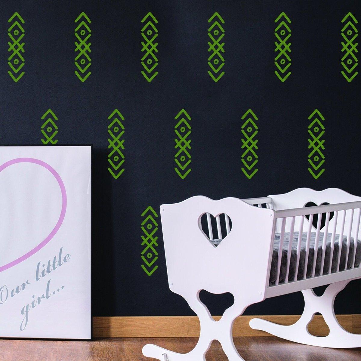 Green arrow wall stickers on black wall, stylish nursery decor with white crib and art print.