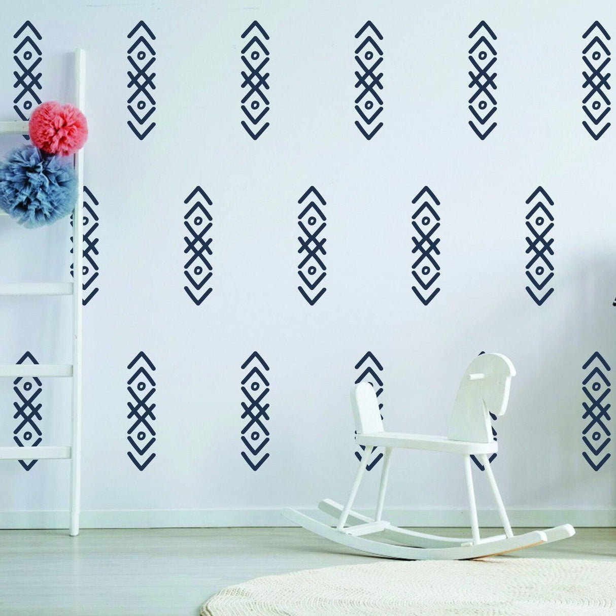 WhimsyArrows vinyl wall decals in navy on a nursery wall with a white rocking horse and decorative pom-poms.