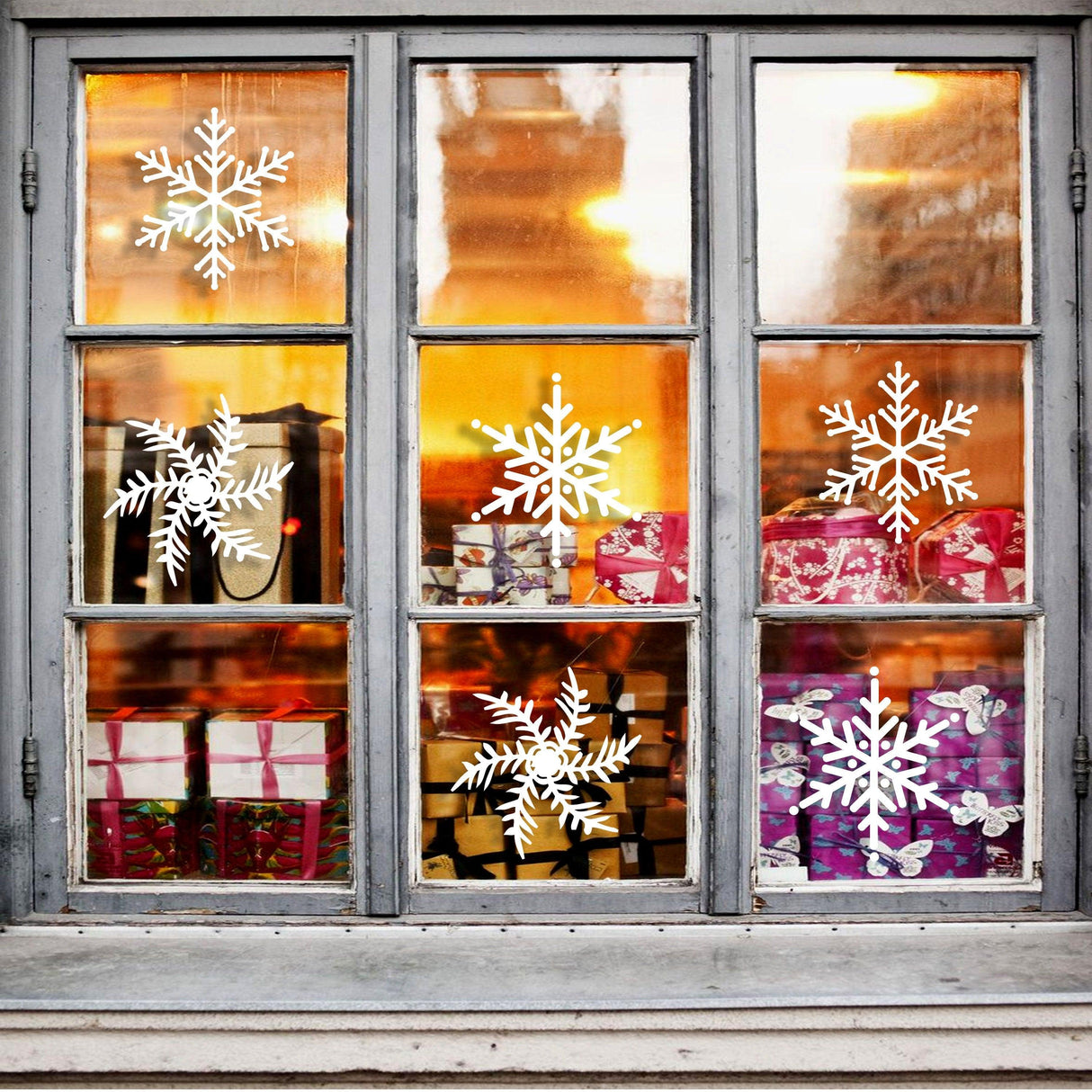 Elegant snowflake window decals in a cozy, festive setting with holiday gifts inside.