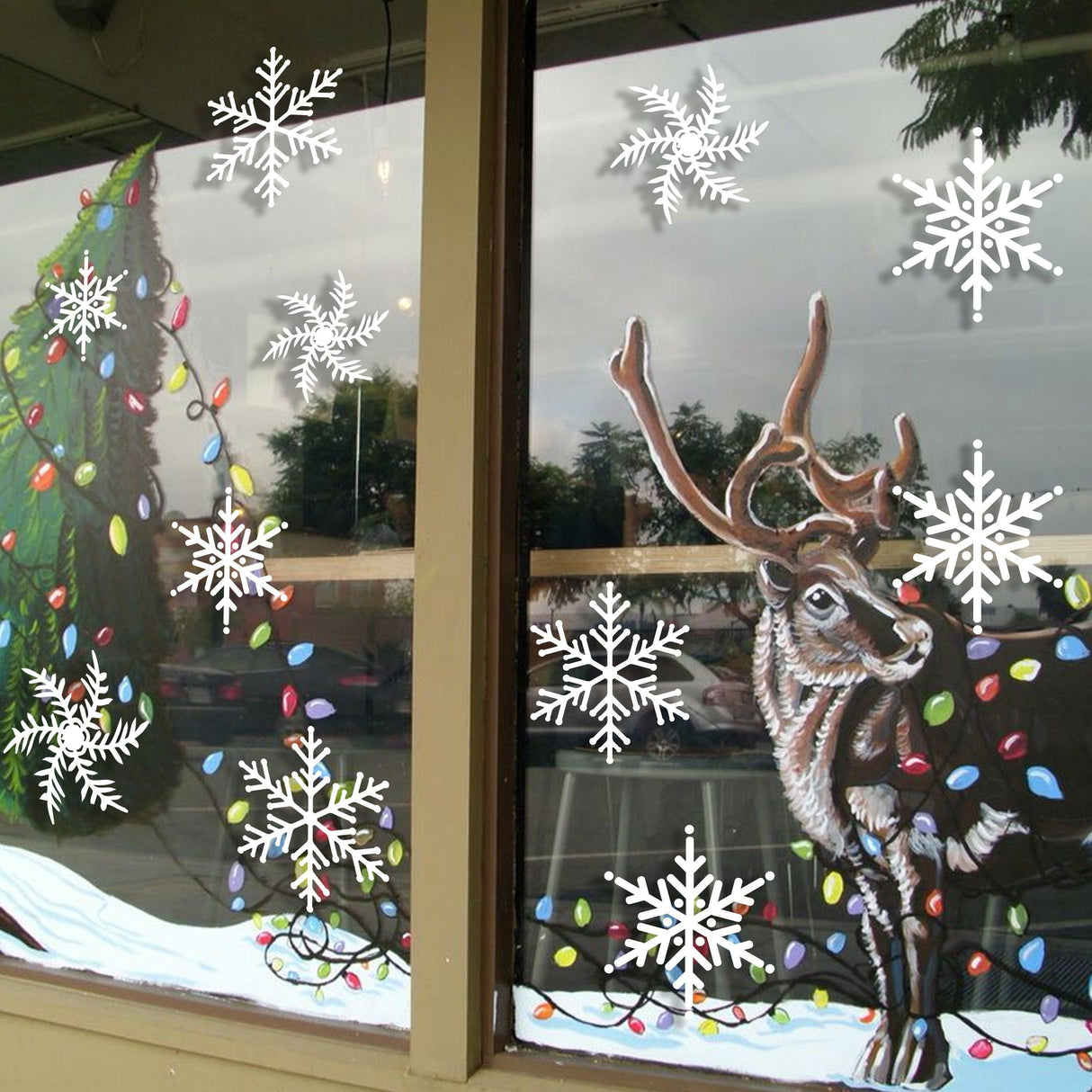 Beautiful winter window display with snowflake stickers and a reindeer, perfect for holiday decor.