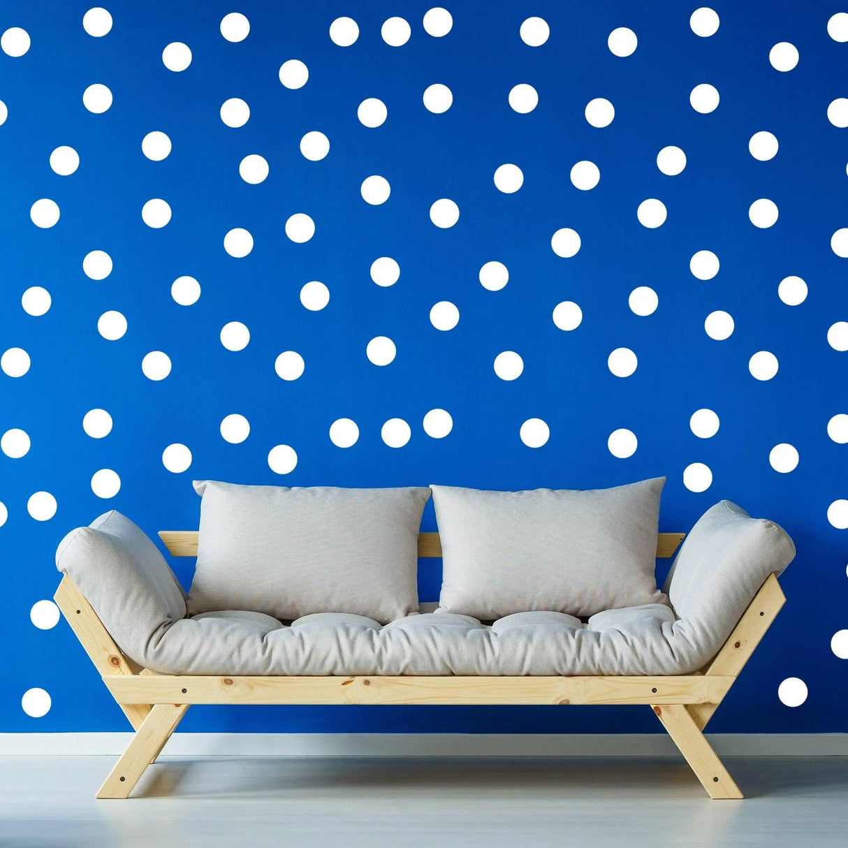 Cozy living room with white round circle dot stickers on a blue wall and a modern wooden sofa.