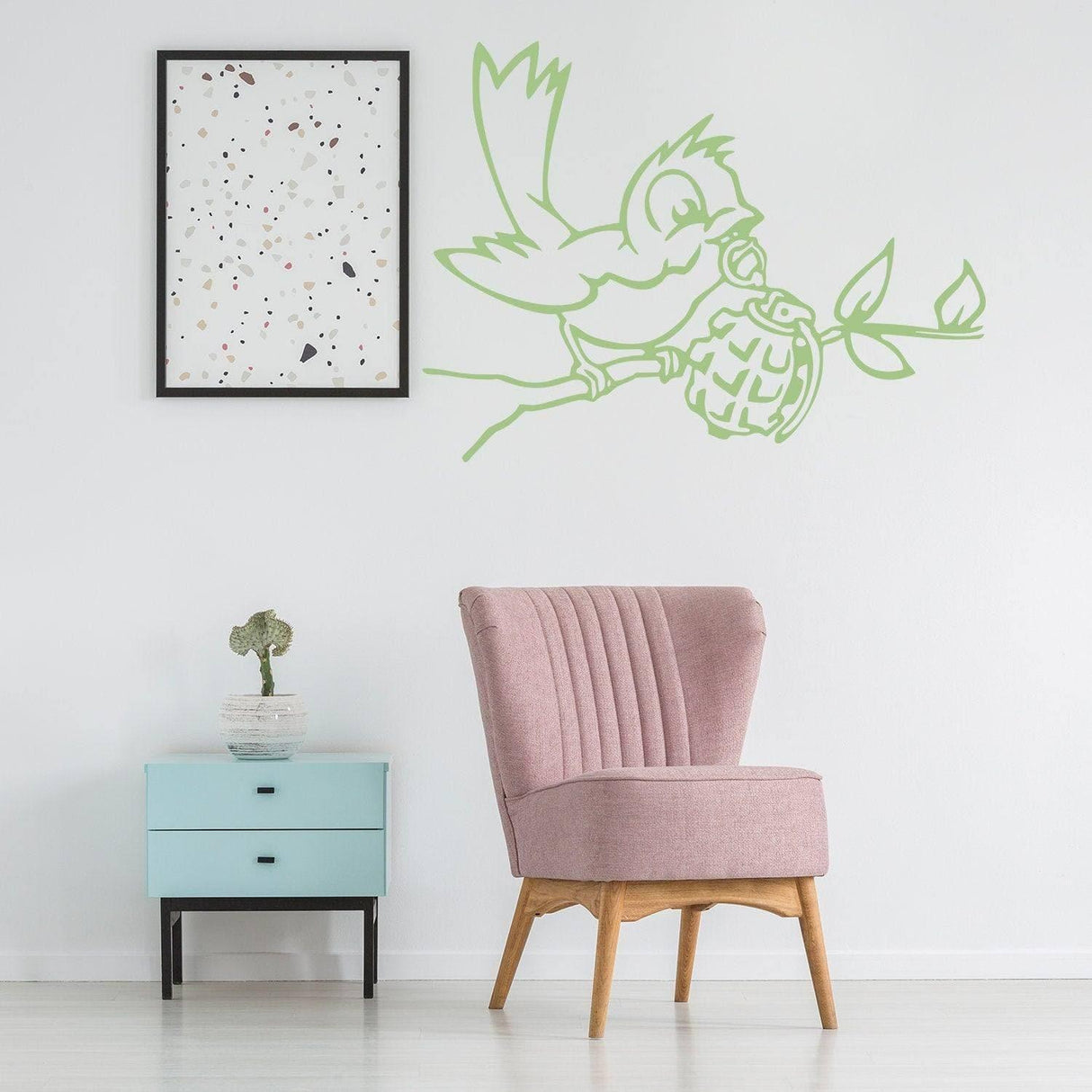 Banksy bird wall decal with grenade design above a pink chair and blue side table in a stylish room.