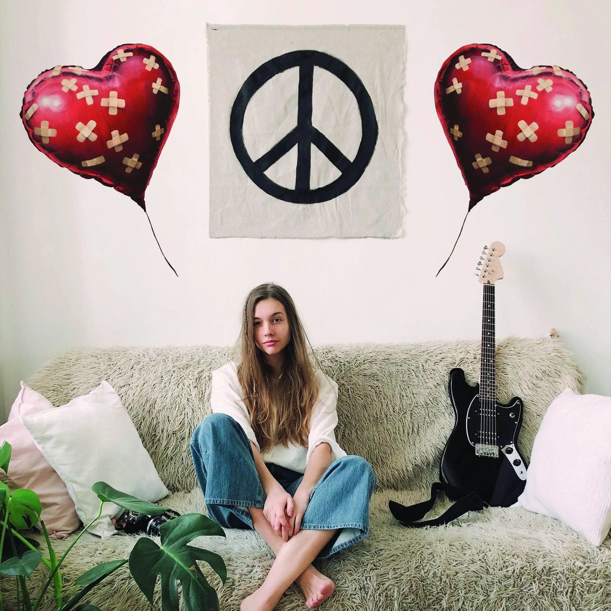 Stylish modern urban living room with heart balloon wall stickers, peace sign art, and a cozy sofa.