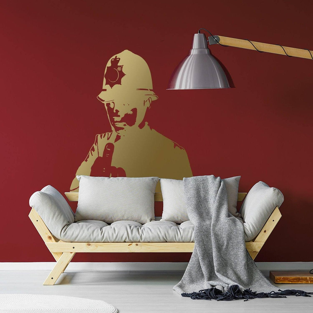 Scotland Yard cop wall decal in gold on red wall behind a stylish couch, adding urban street art decor.