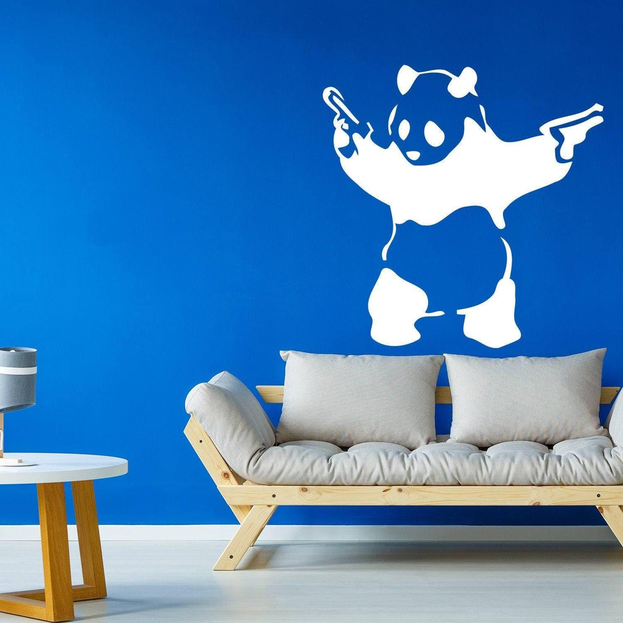 White panda wall decal holding guns on a blue wall, adding urban art flair to modern interior decor.