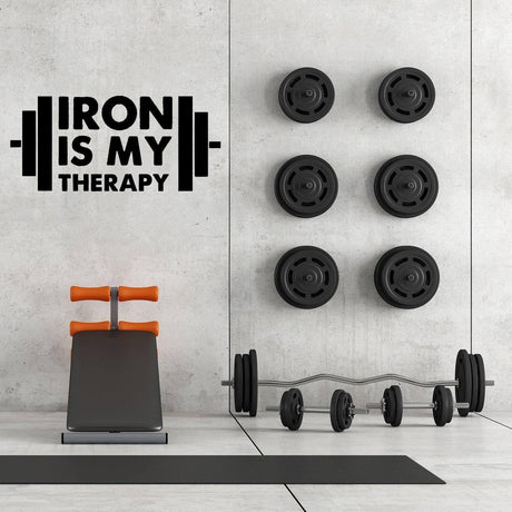 Inspirational gym wall art decal 'Iron is My Therapy' above weights and workout bench in a modern gym setting.
