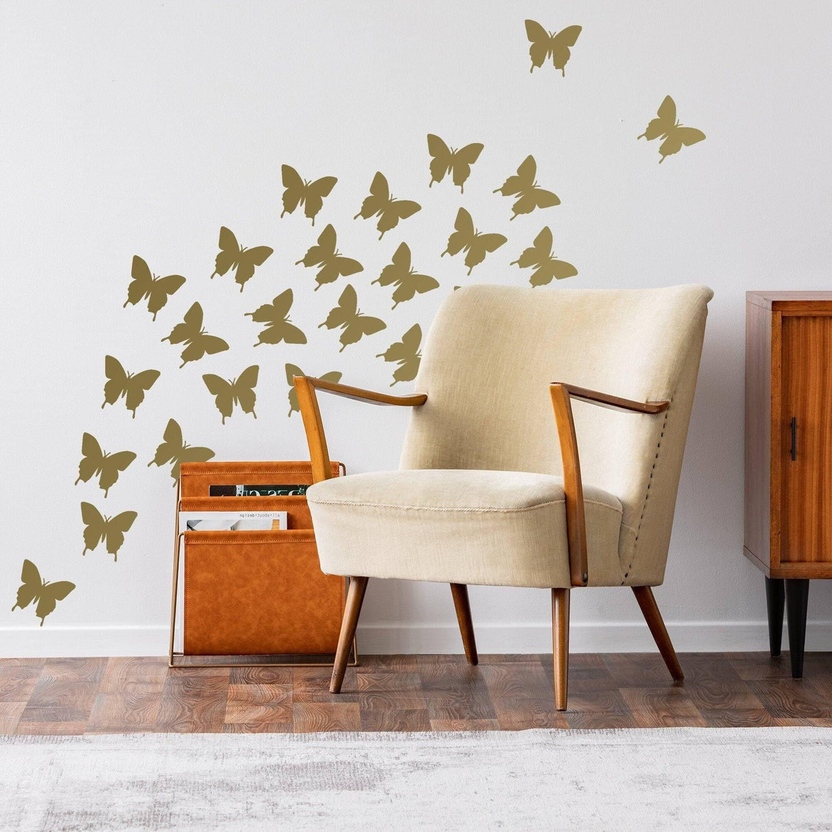 Butterfly wall decals in gold design, enhancing a cozy living room with a beige armchair and wooden decor.