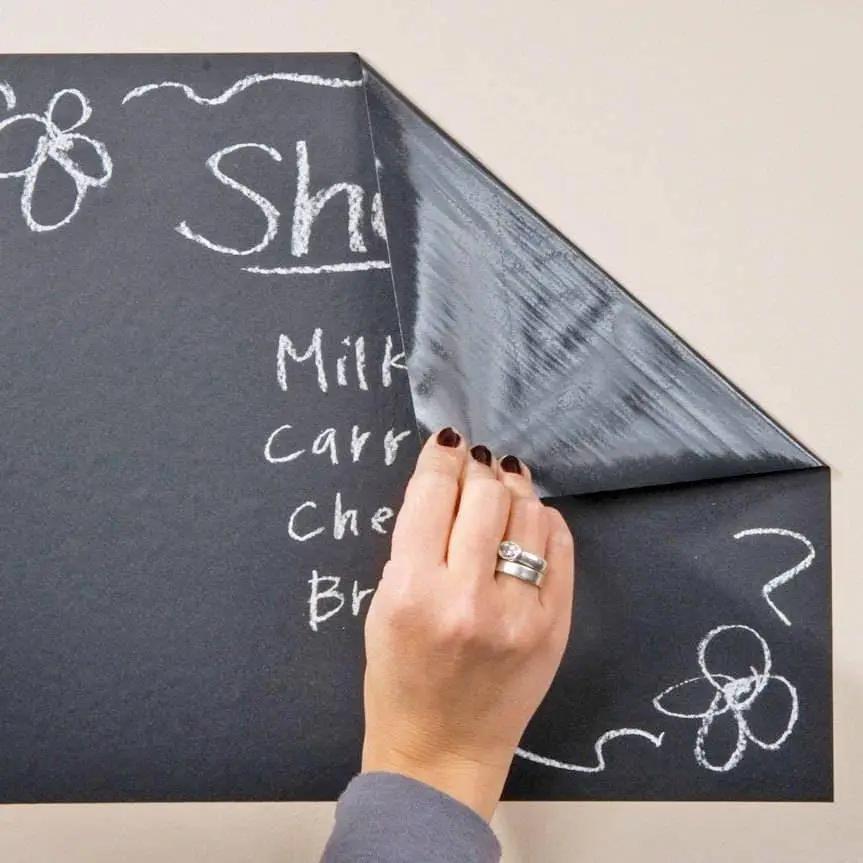Person peeling back a luxurious chalkboard wall sticker with handwritten notes.