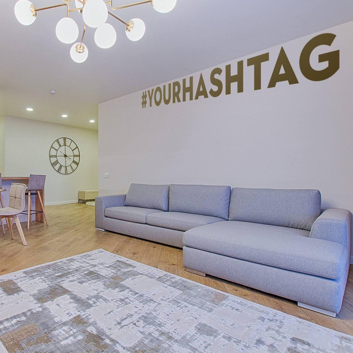 Living room with gray sofa, hashtag wall decal #YOURHASHTAG, and modern lighting fixtures.
