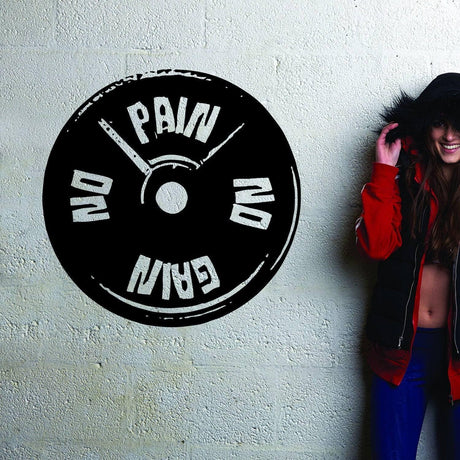 Inspirational workout decal saying 'No Pain No Gain' on a textured wall with a woman in stylish workout attire.