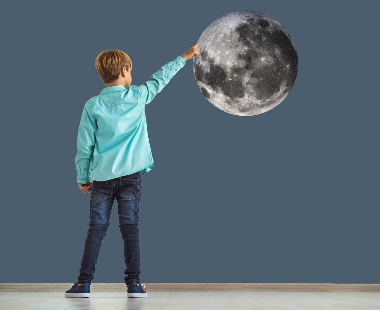 Child reaching for a large moon wall sticker in a decorated room, showcasing lunar cycle wall art.