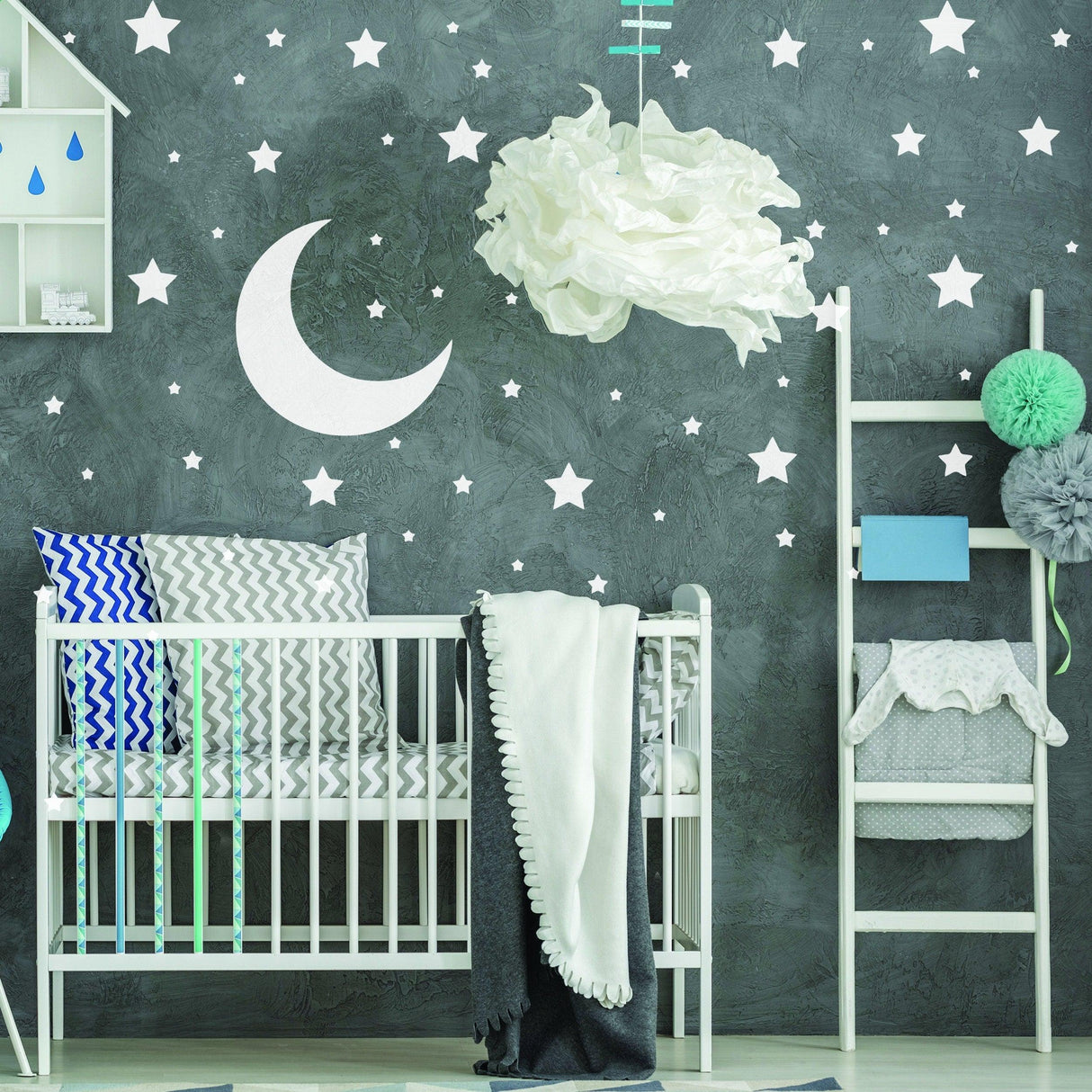 Nursery room with white stars and moon wall stickers, crib with soft blankets and decorative elements.
