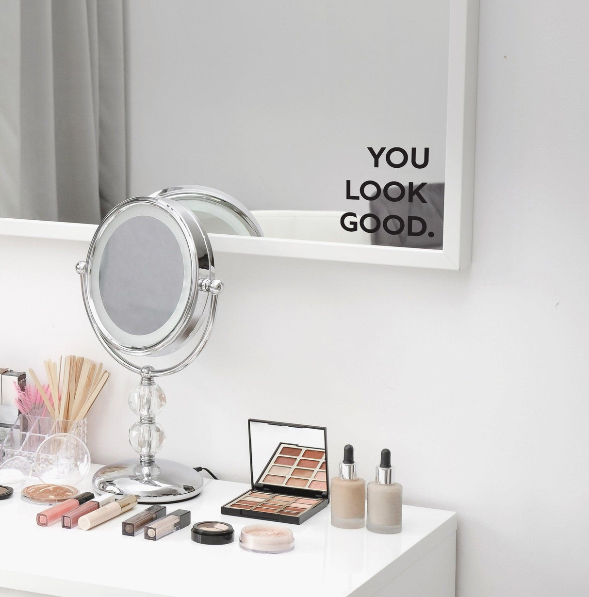 You Look Good Square Mirror Decal on a bathroom mirror above a vanity with makeup products.