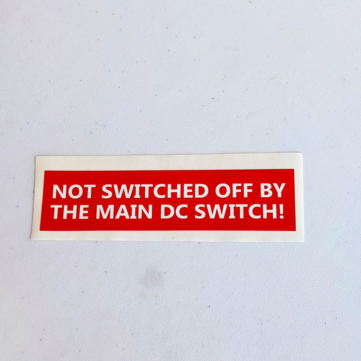 Safety label decal warning 'Not Switched Off by Main DC Switch' in red, ideal for electrical safety compliance.