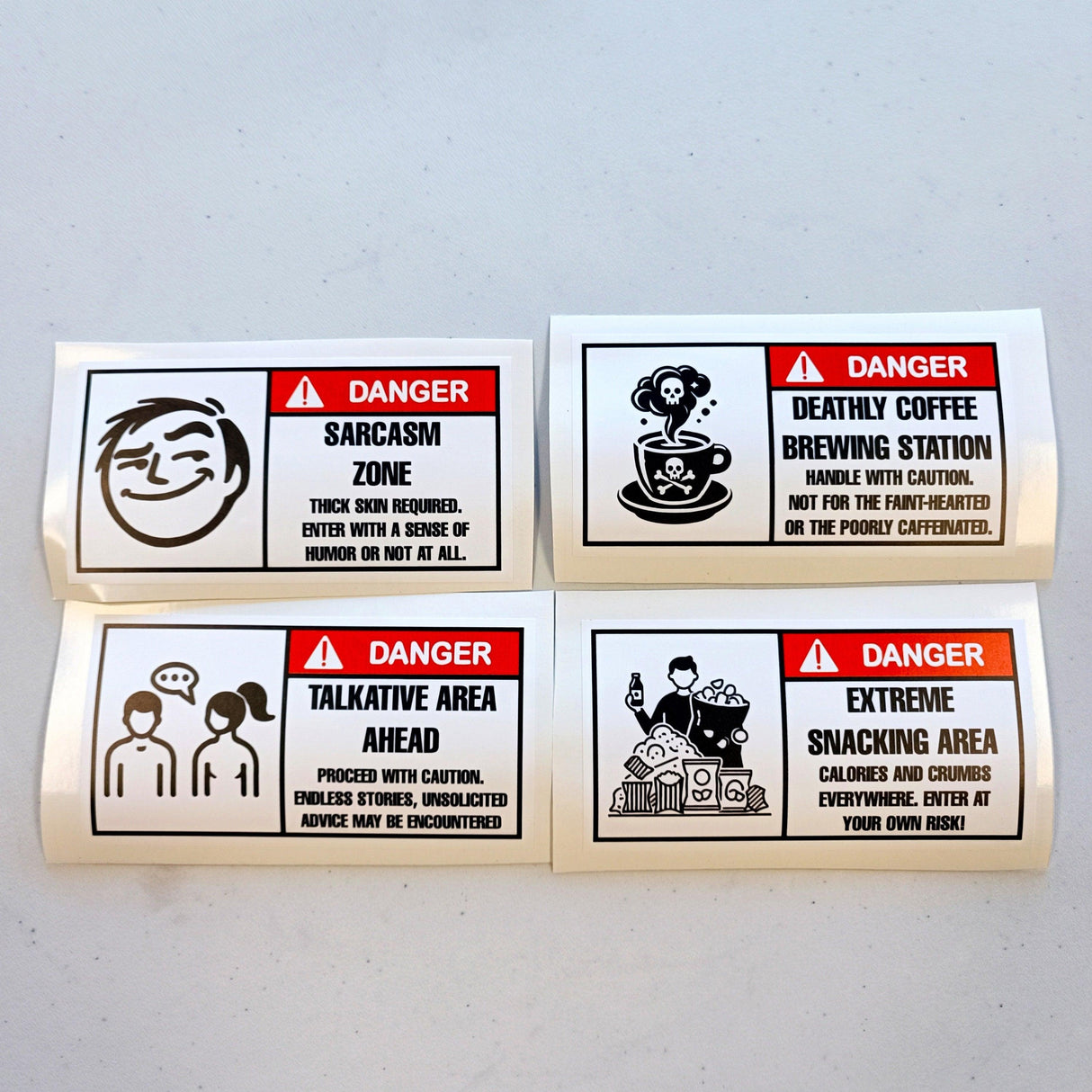 Set of 4 humorous danger warning label stickers featuring sarcasm, talkative area, coffee brewing, and snacking signs.