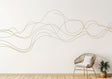 Elegant line art wall sticker in gold, adding a modern touch to a minimalist room with chair and plant.