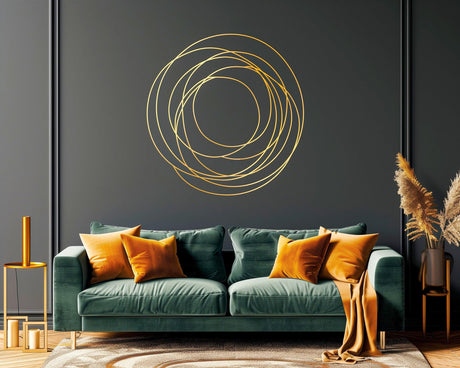 Elegant gold circle wall sticker on dark wall above a modern green sofa with orange cushions, enhancing contemporary decor.