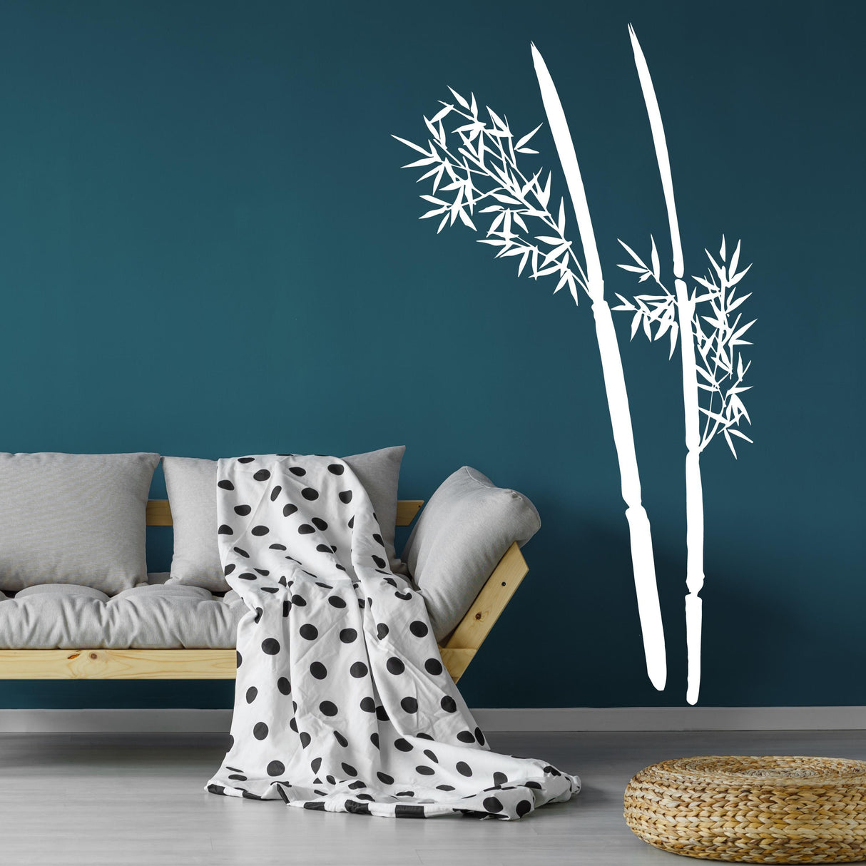 Bamboo wall decal on teal wall above sofa with polka dot blanket, minimalist Asian-inspired decor for a calming atmosphere.
