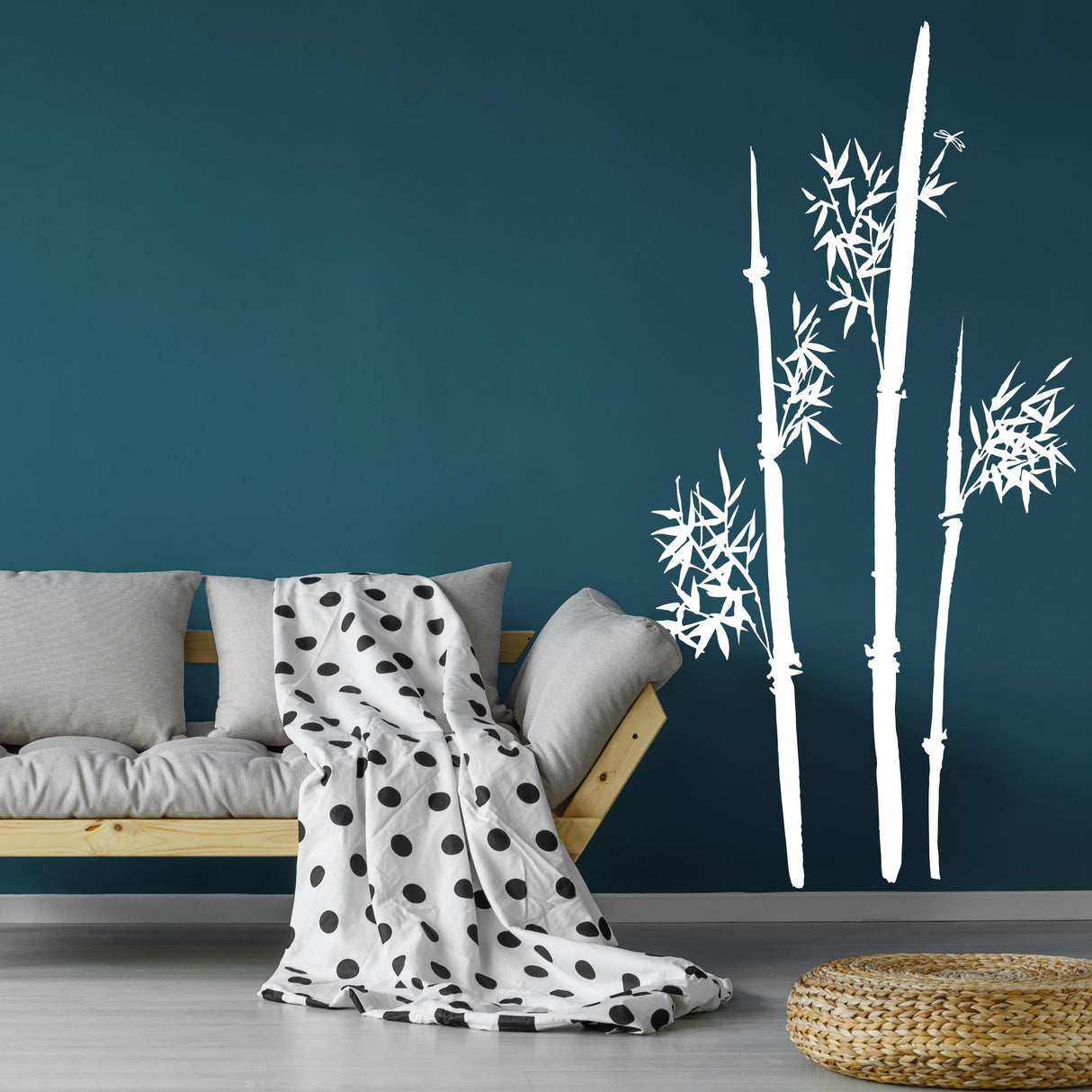 Minimalist bamboo wall decal in a modern living room with a polka dot blanket and blue wall.