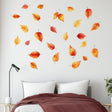 Wall displaying 25 autumn leaves decals in warm colors, enhancing cozy bedroom decor for fall.