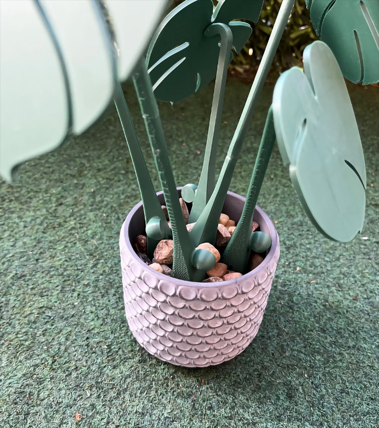 3D printed Monstera leaf plant in textured pot with pebbles, adding stylish decor to home surfaces.