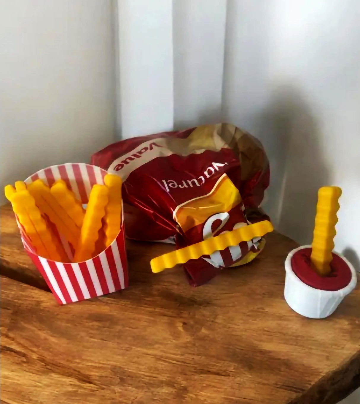 Fun French fry snack sealers and ketchup cannon next to a snack bag on a wooden surface.