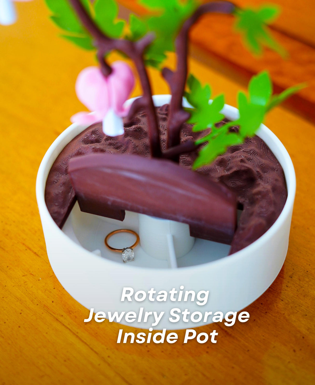 Rotating jewelry storage inside a flower pot design, featuring delicate bleeding hearts and hidden compartments.