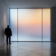 Person standing beside a frosted glass wall with a gradient sky view, showcasing elegance and privacy.