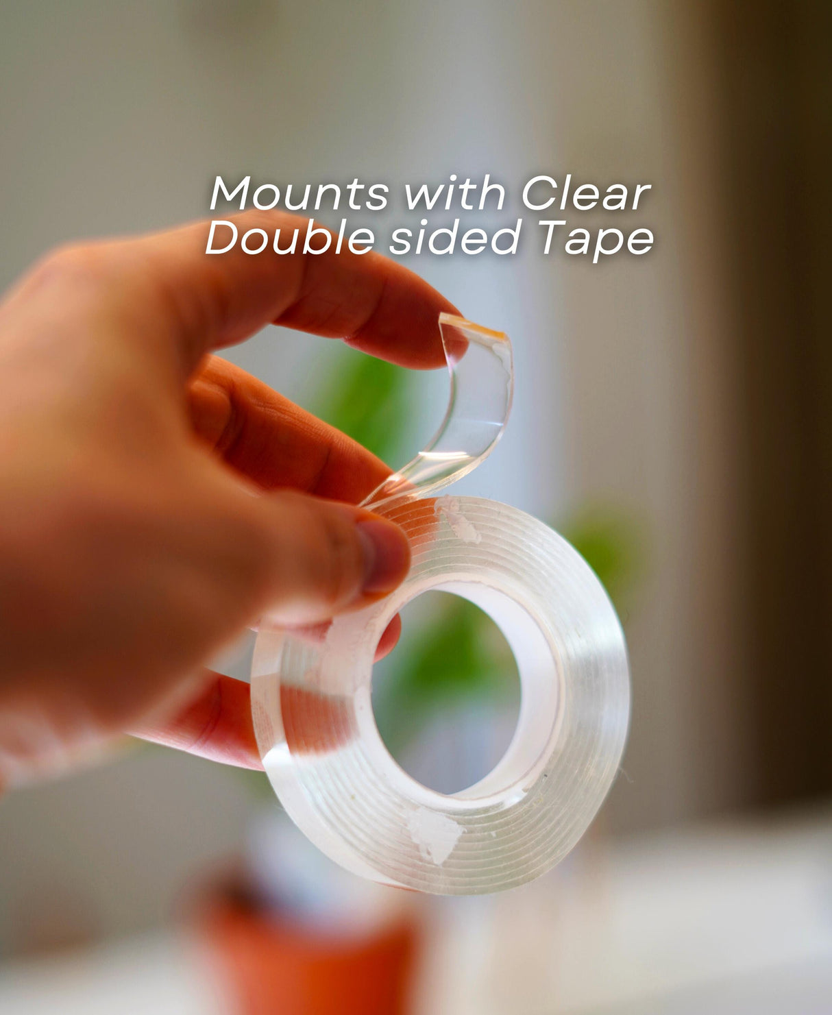 Hand holding clear double-sided tape for mounting accessories securely.