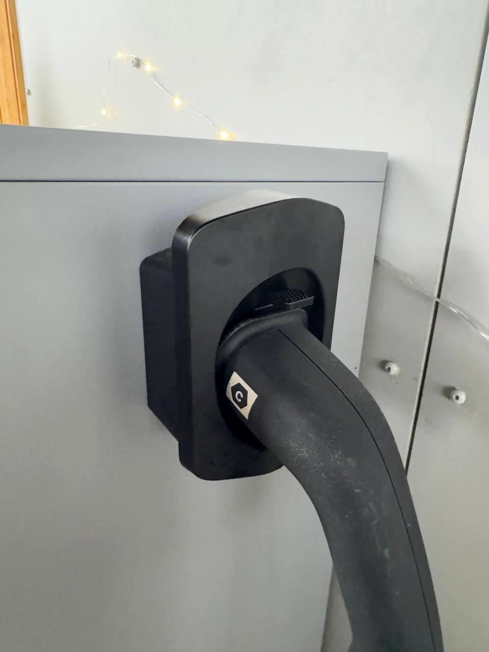 Close-up of an electric car charger connector holder mounted on a wall, showcasing its sleek design and secure fit.