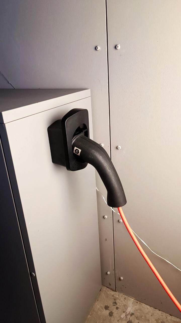 Electric car charger connector securely mounted on a wall, showcasing an organized EV charging area.