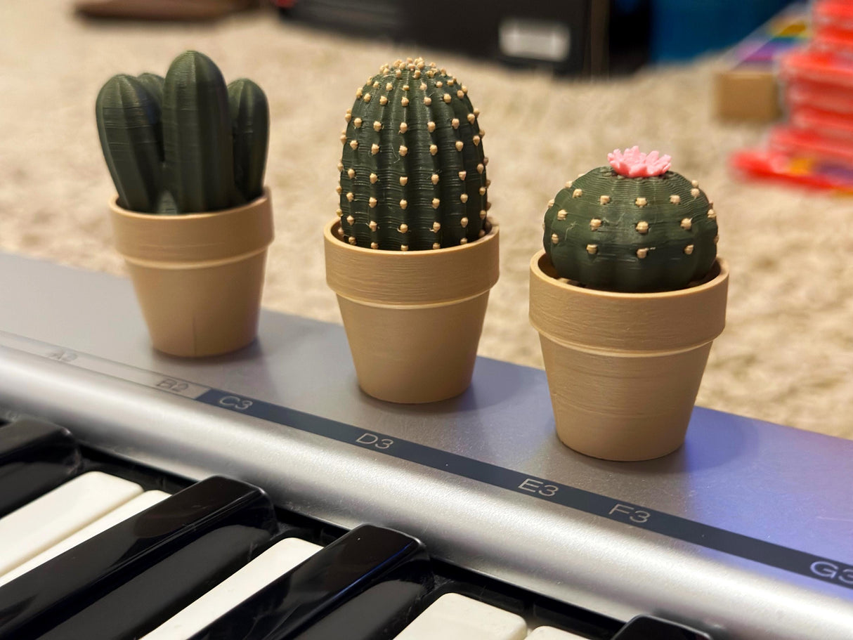 Mini Clickable Cacti in pots on a keyboard, fun mechanical fidget toys for desk decor and stress relief.