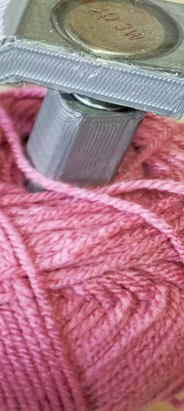 Close-up of a yarn spinner holding pink yarn, showcasing a crochet tool organizer for smooth crafting.