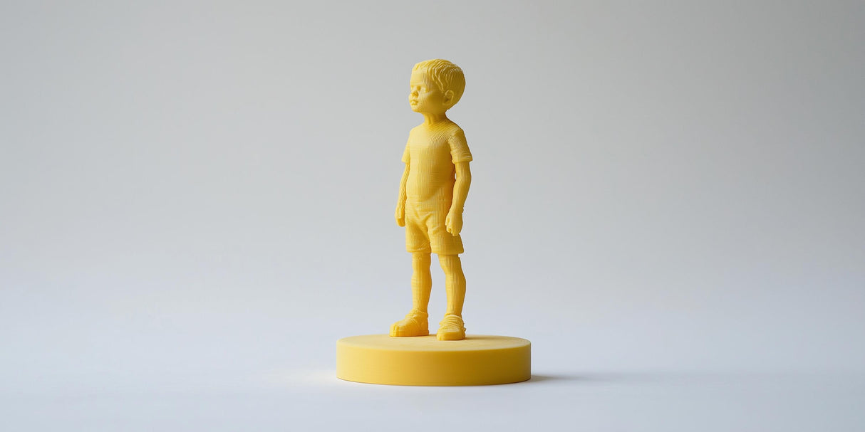 Custom 3D printed yellow figurine of a young boy standing on a round base, showcasing personalized design.