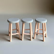 Three 3D printed miniature bar stools for dollhouses, with round seats and slender legs, styled in pastel colors.