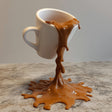 3D printed floating spilling coffee cup sculpture creating an optical illusion effect for unique kitchen decor.