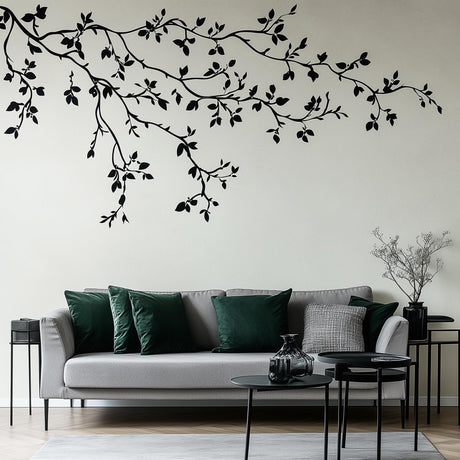 Minimalist black branch wall decal above a modern gray sofa with green cushions in a stylish living room.