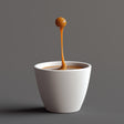 3D-printed floating espresso macchiato drop sculpture in a minimalist white cup.