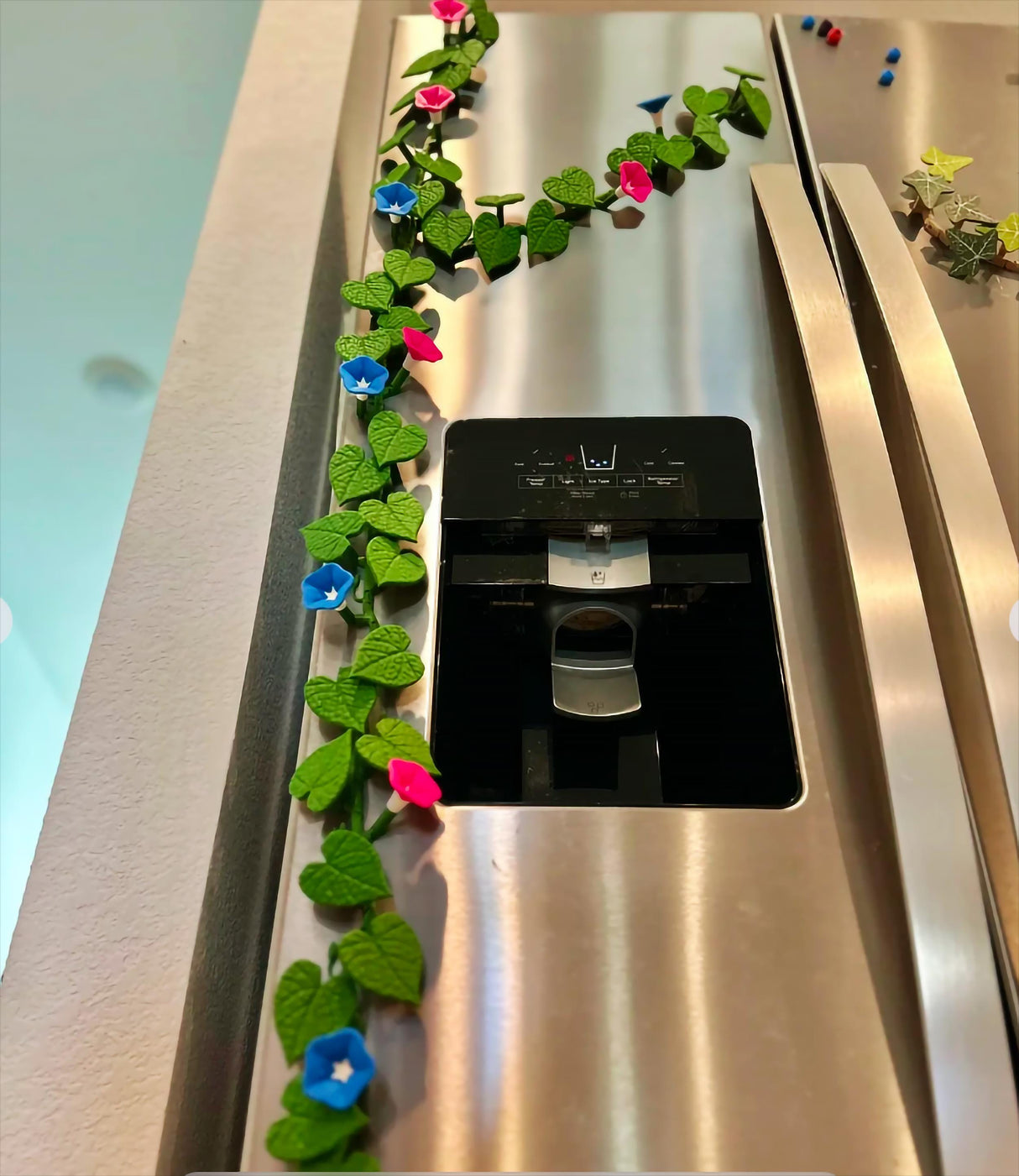 Colorful Morning Glory fridge magnets featuring ivy vines and flowers decorating a stainless steel refrigerator.