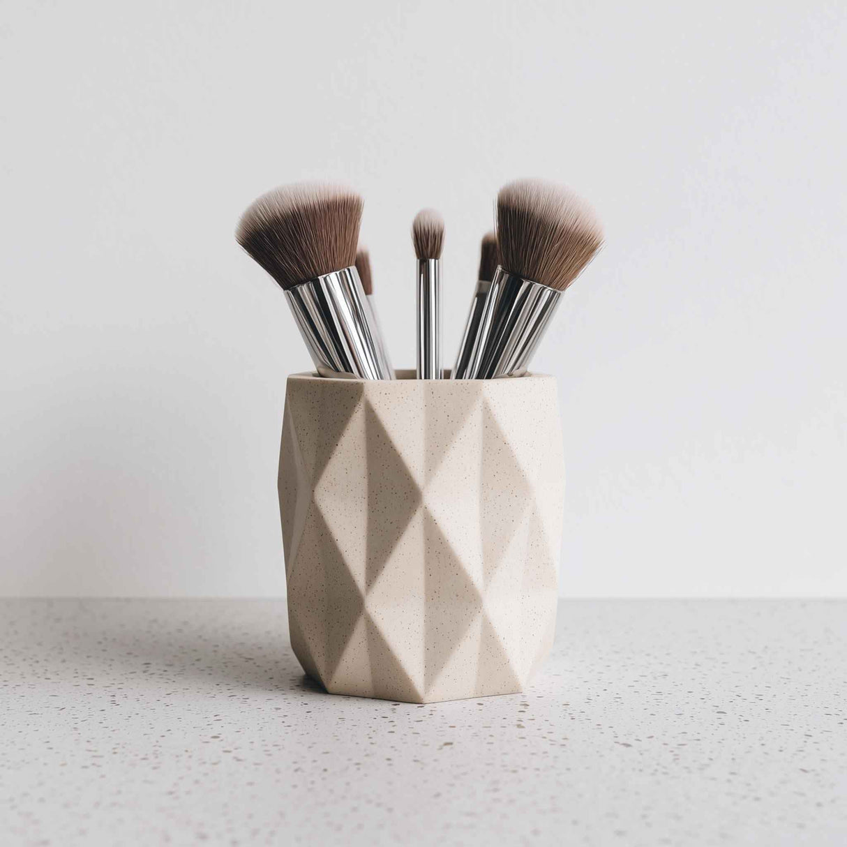 Light beige 3D printed geometric faceted holder, styled with makeup brushes for illustration; brushes are not included.