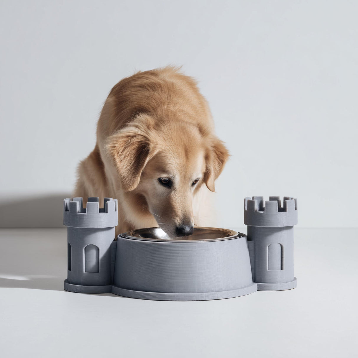 3D printed castle turret pet bowl holder stand with two tower sides and a central bowl opening, shown with a dog eating from a metal bowl in a studio setting.