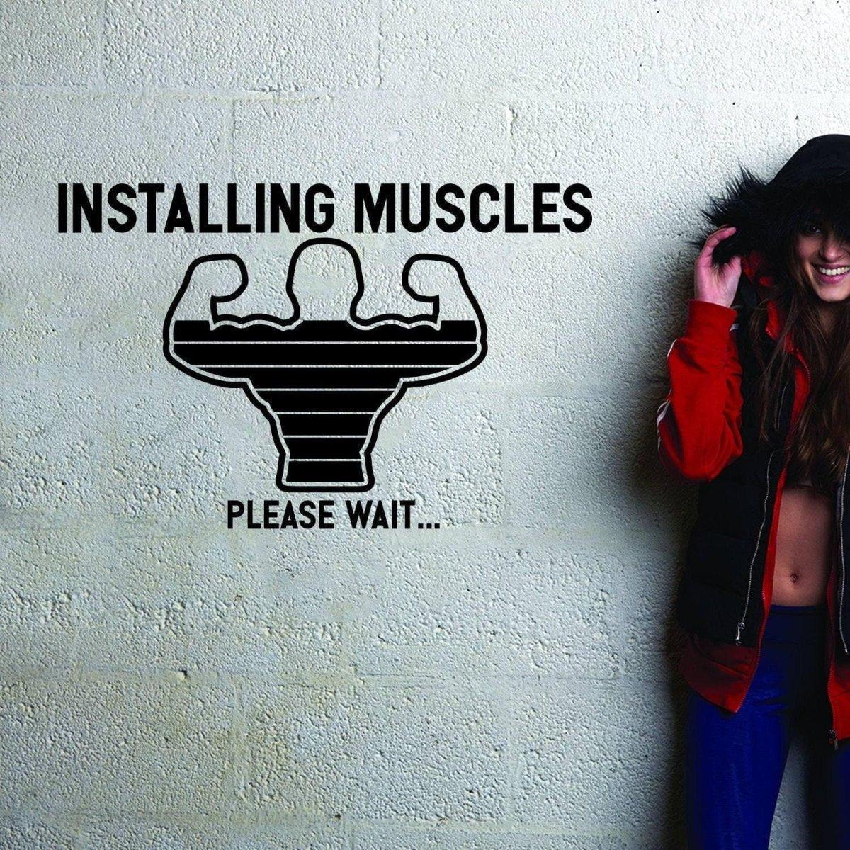 A motivational wall decal featuring a graphic of flexing muscles with the text 'INSTALLING MUSCLES PLEASE WAIT...' for gym decor.