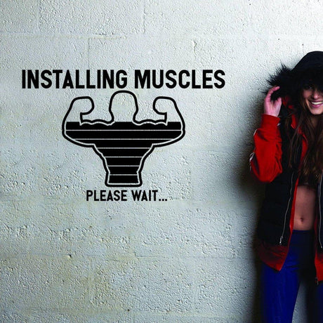 A motivational wall decal featuring a graphic of flexing muscles with the text 'INSTALLING MUSCLES PLEASE WAIT...' for gym decor.