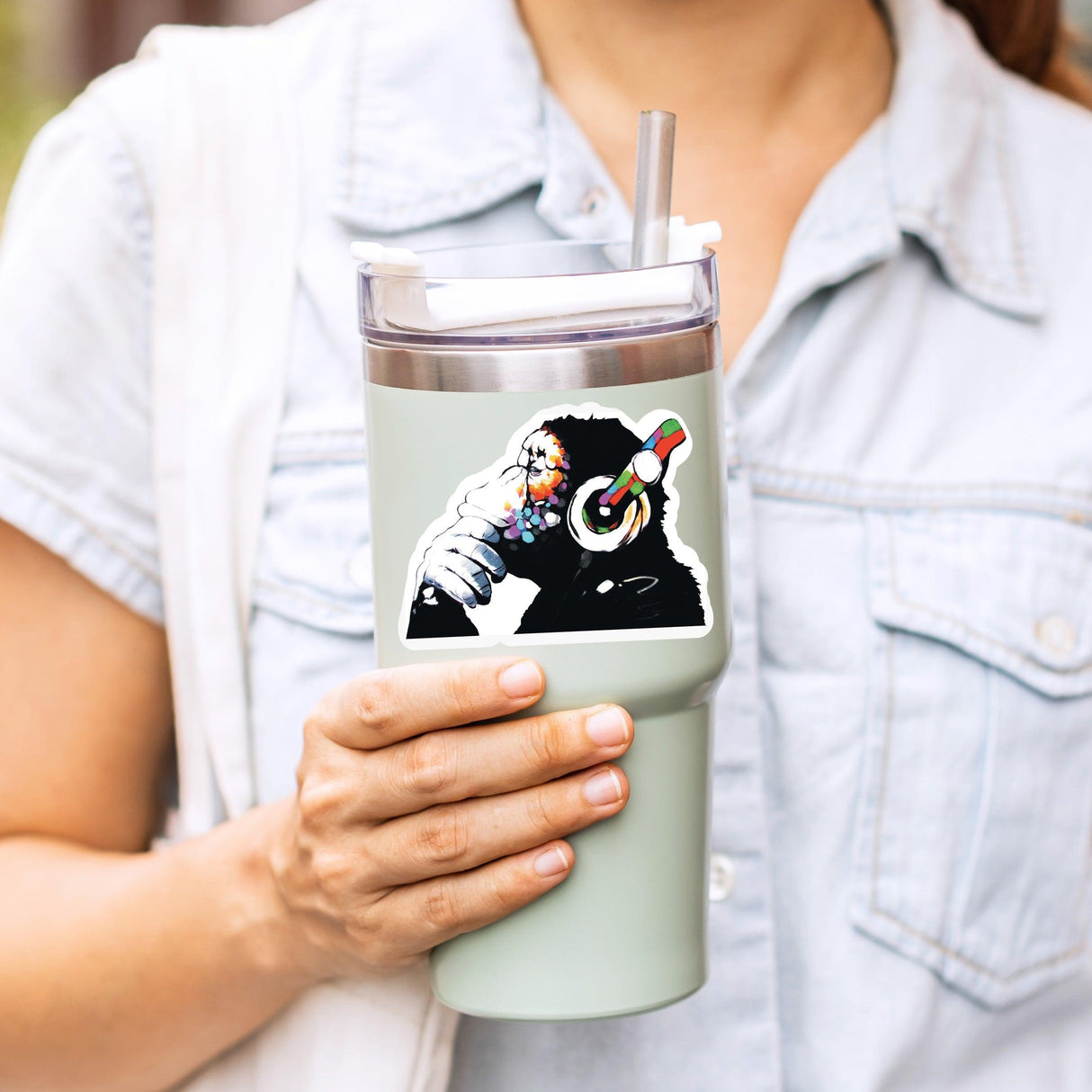 Person holding a tumbler with a cool music monkey vinyl decal featuring a chimp wearing colorful headphones.