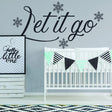 Inspirational wall sticker with 'Let it go' text and snowflakes above a crib in a cozy nursery.