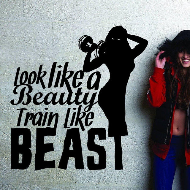 Motivational wall sticker design featuring silhouette and quote: 'Look like a Beauty, Train like a Beast' in a fitness setting.