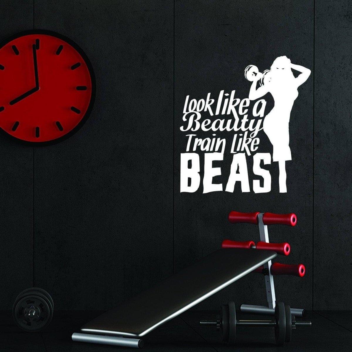 Motivational fitness wall decal saying 'look like a beauty train like a beast' in a gym setting.