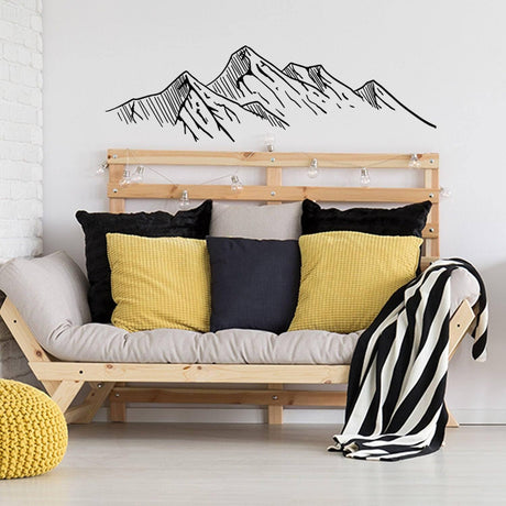 Mountain silhouette wall decal above a cozy seating area with pillows, adding a touch of nature to interior decor.