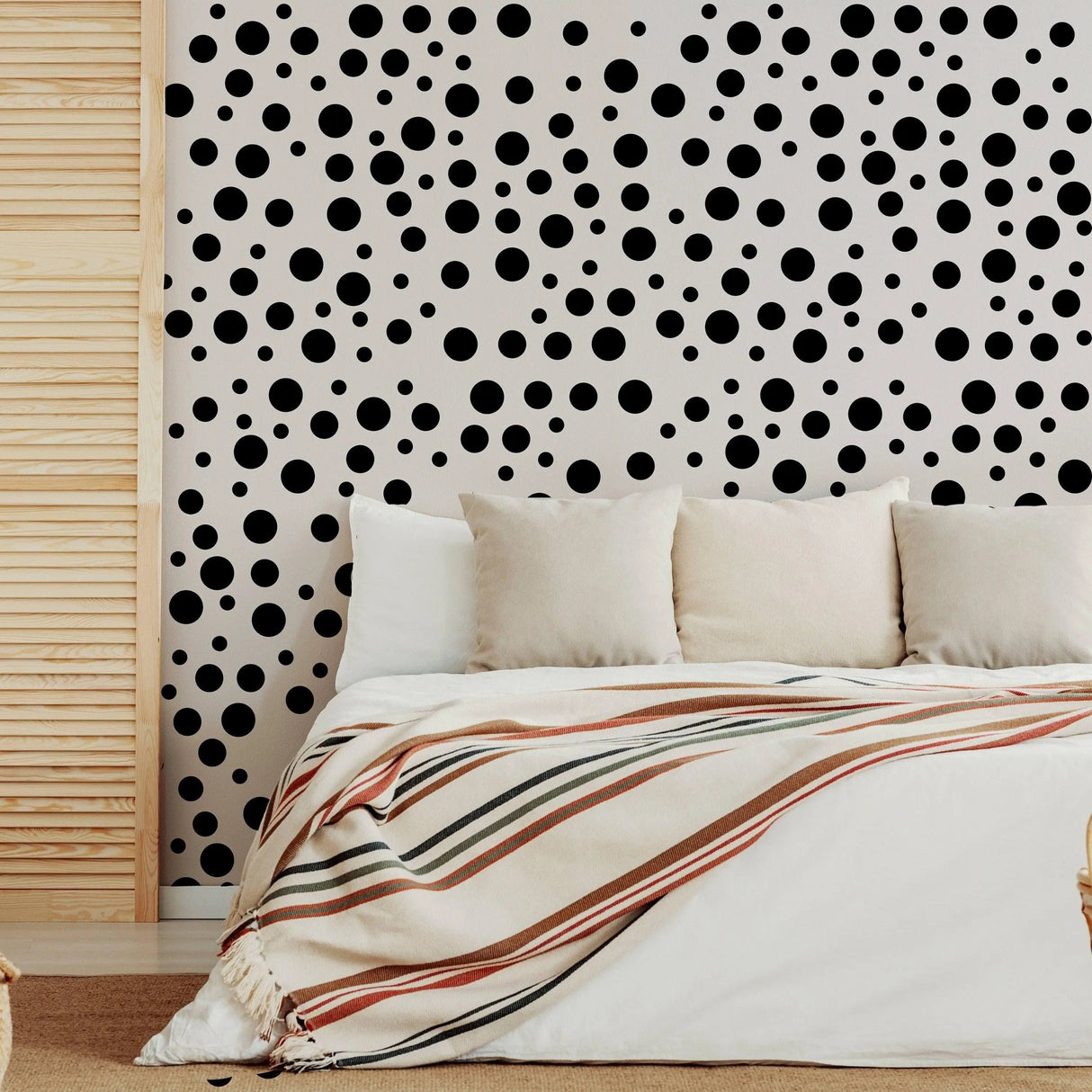 Black polka dot vinyl wall decals on a cozy bedroom wall, adding whimsy to the interior decor.