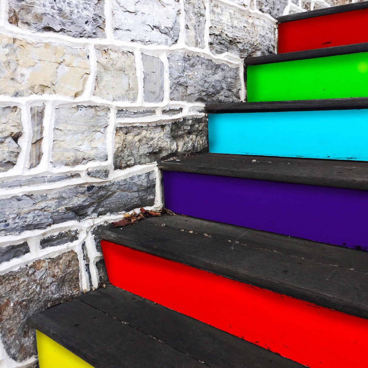 Colorful stair riser decals in rainbow gradient on wooden steps, adding style and vibrancy to dull stairs.